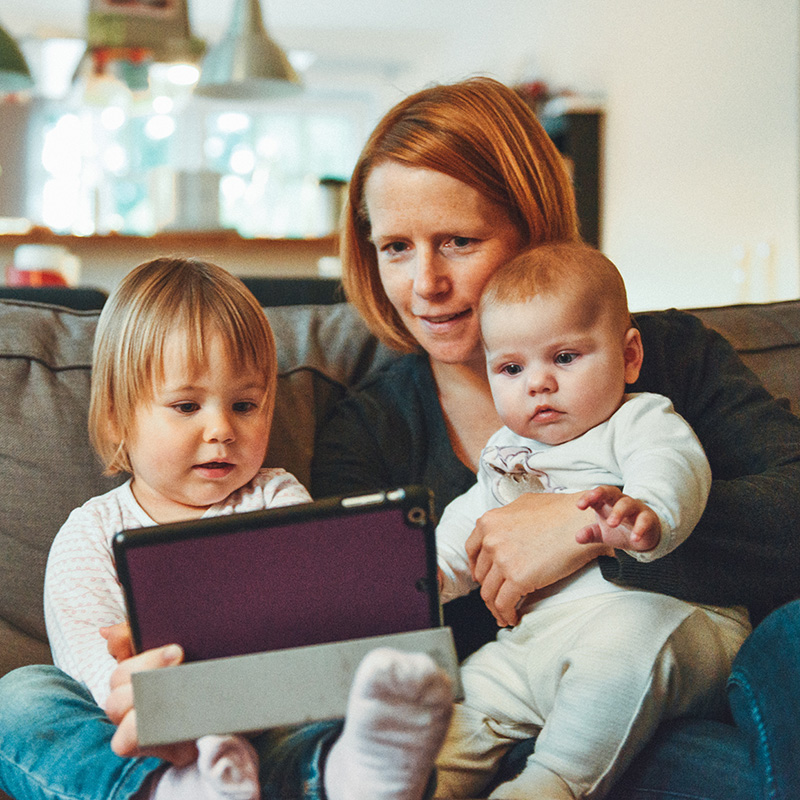 Frau guckt mit Kindern auf Tablet